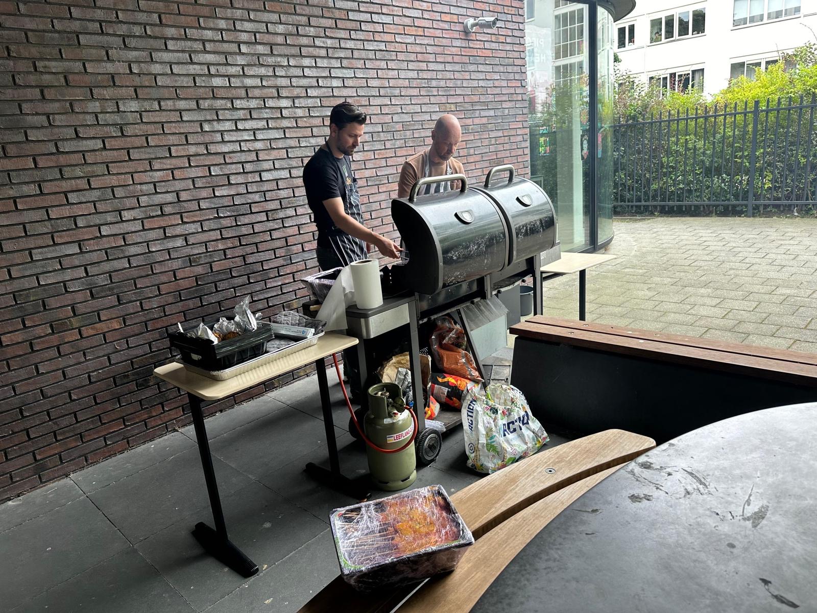 Begeleiders verzorgen de barbecue tijdens een feestelijke buitenafsluiting
