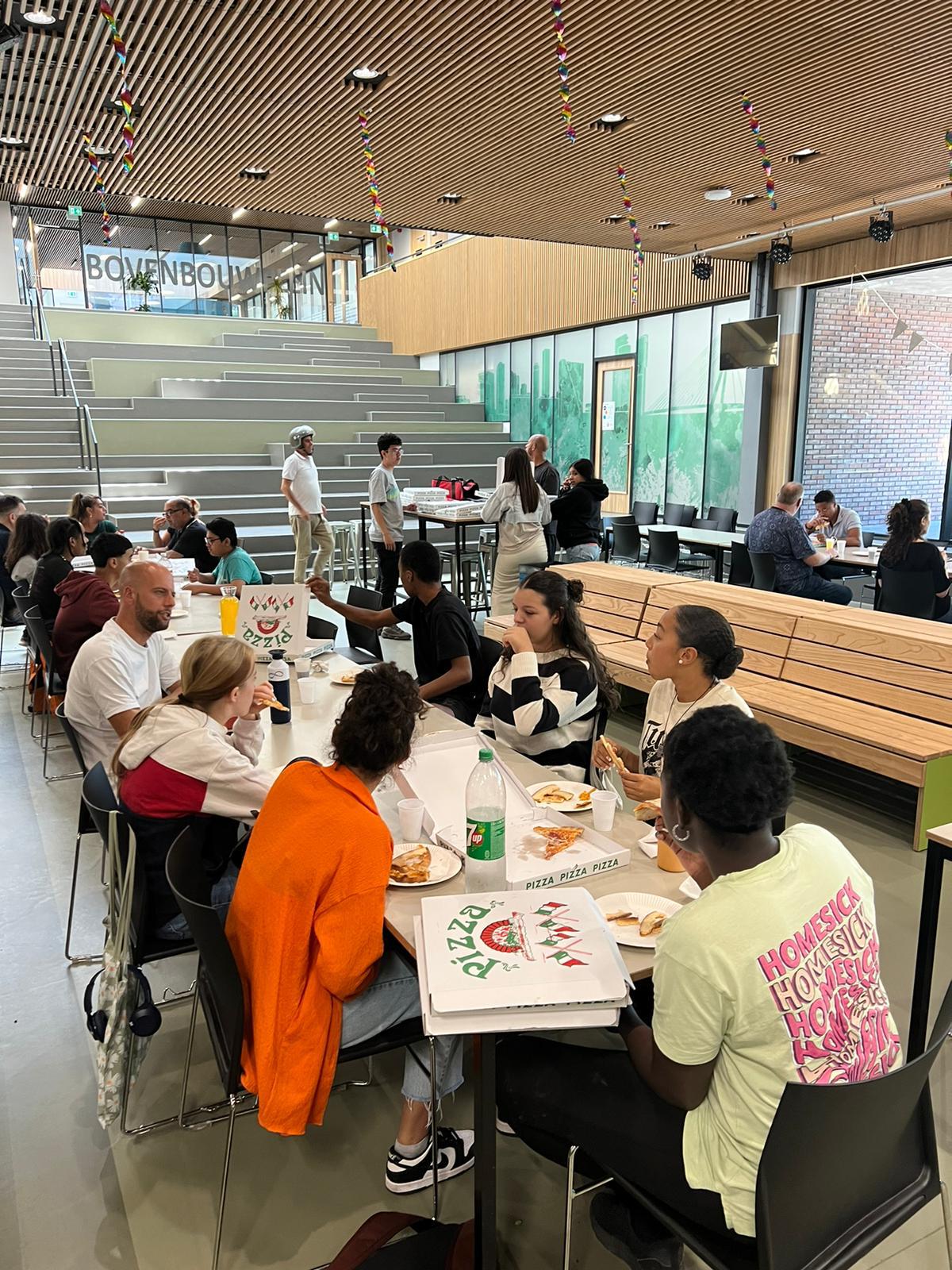 Leerlingen en begeleiders genieten samen van de lunch op het bovenbouwplein