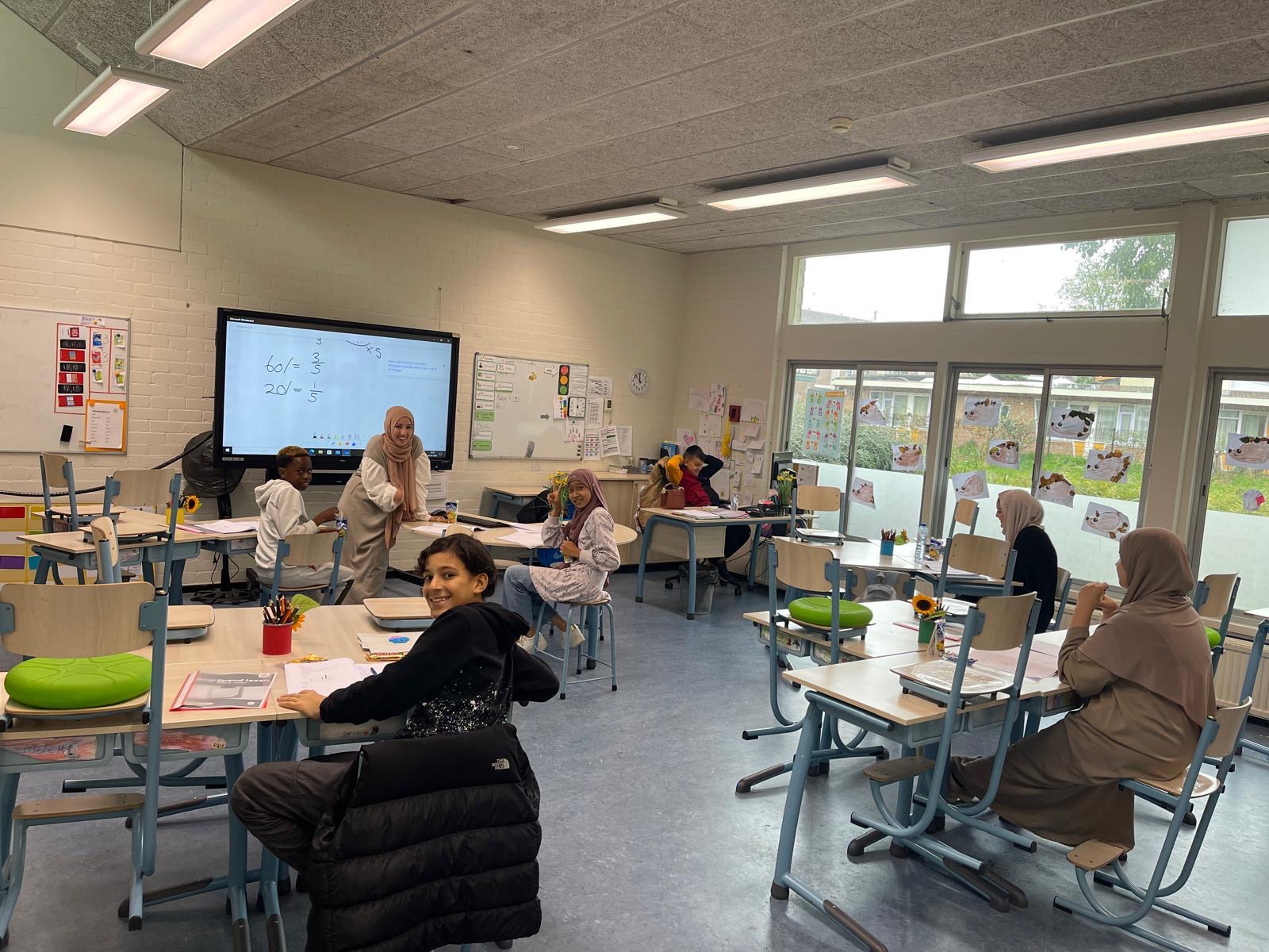 Docent begeleidt basisschoolleerlingen bij rekenen en breuken