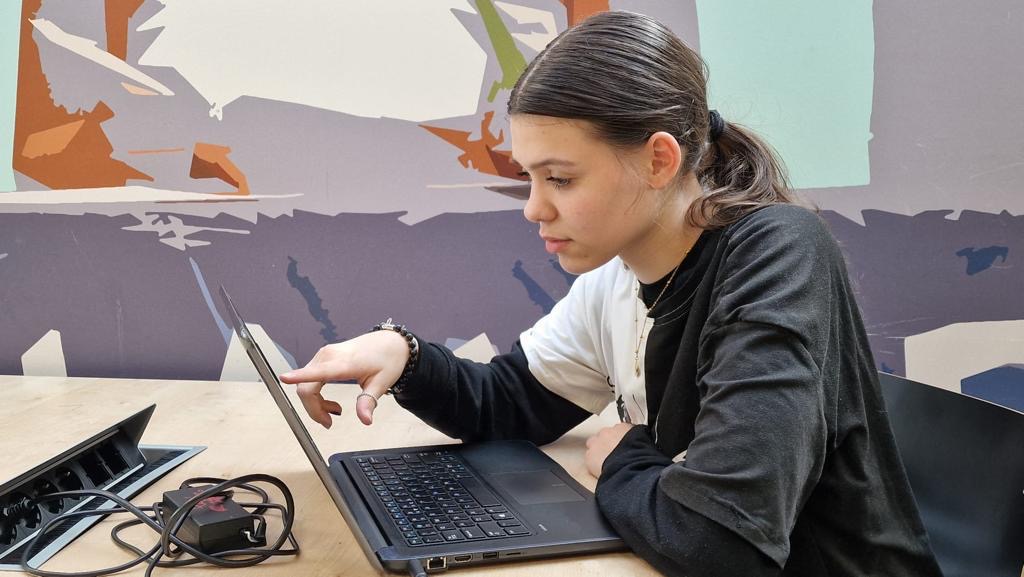 Leerling bespreekt een opdracht op de laptop