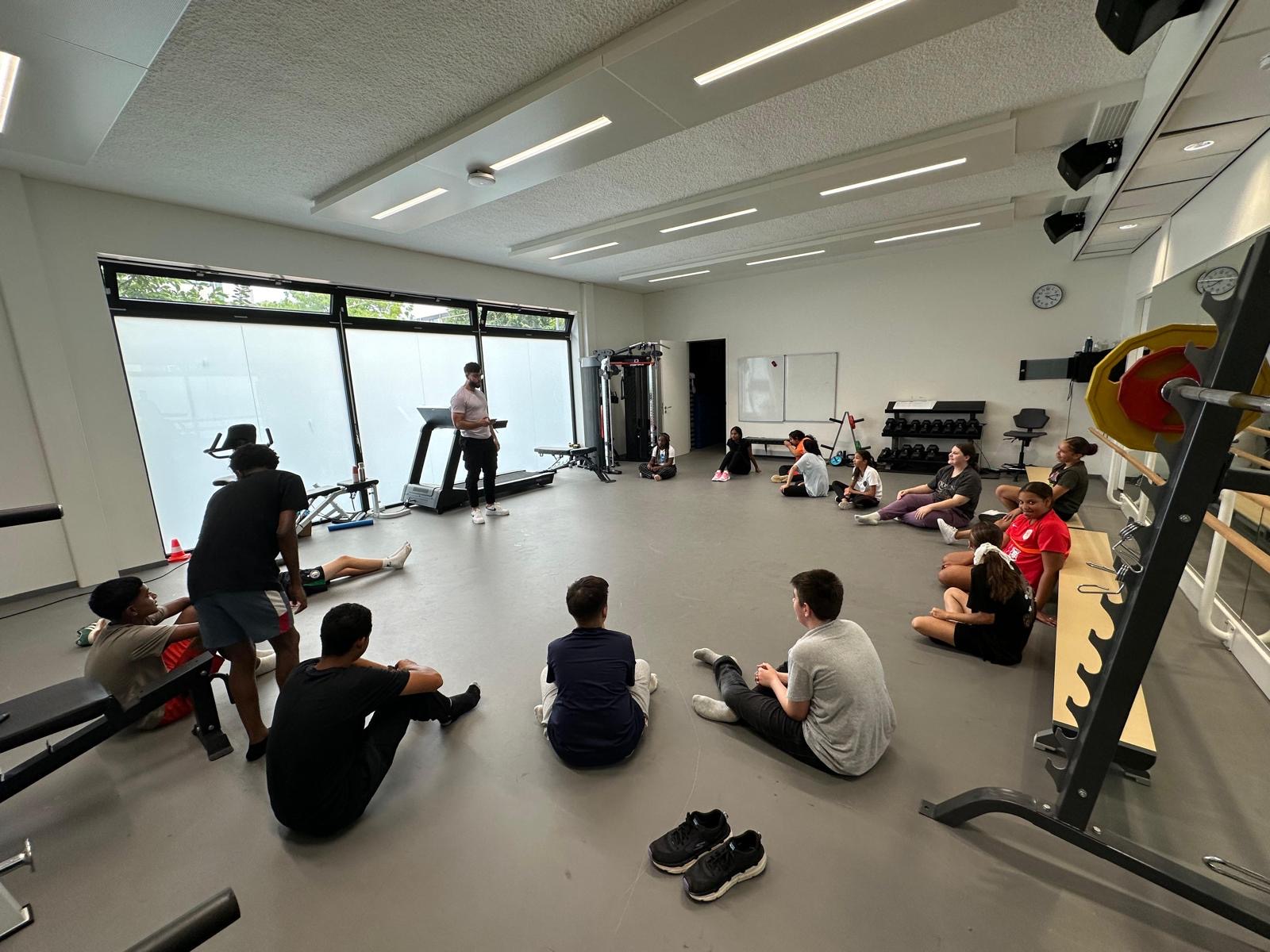 Sportinstructeur geeft uitleg aan leerlingen in de fitnessruimte