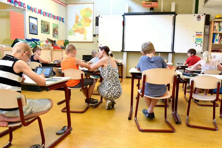 Leerlingen werken aan hun opdrachten in een basisschoolklas met begeleiding