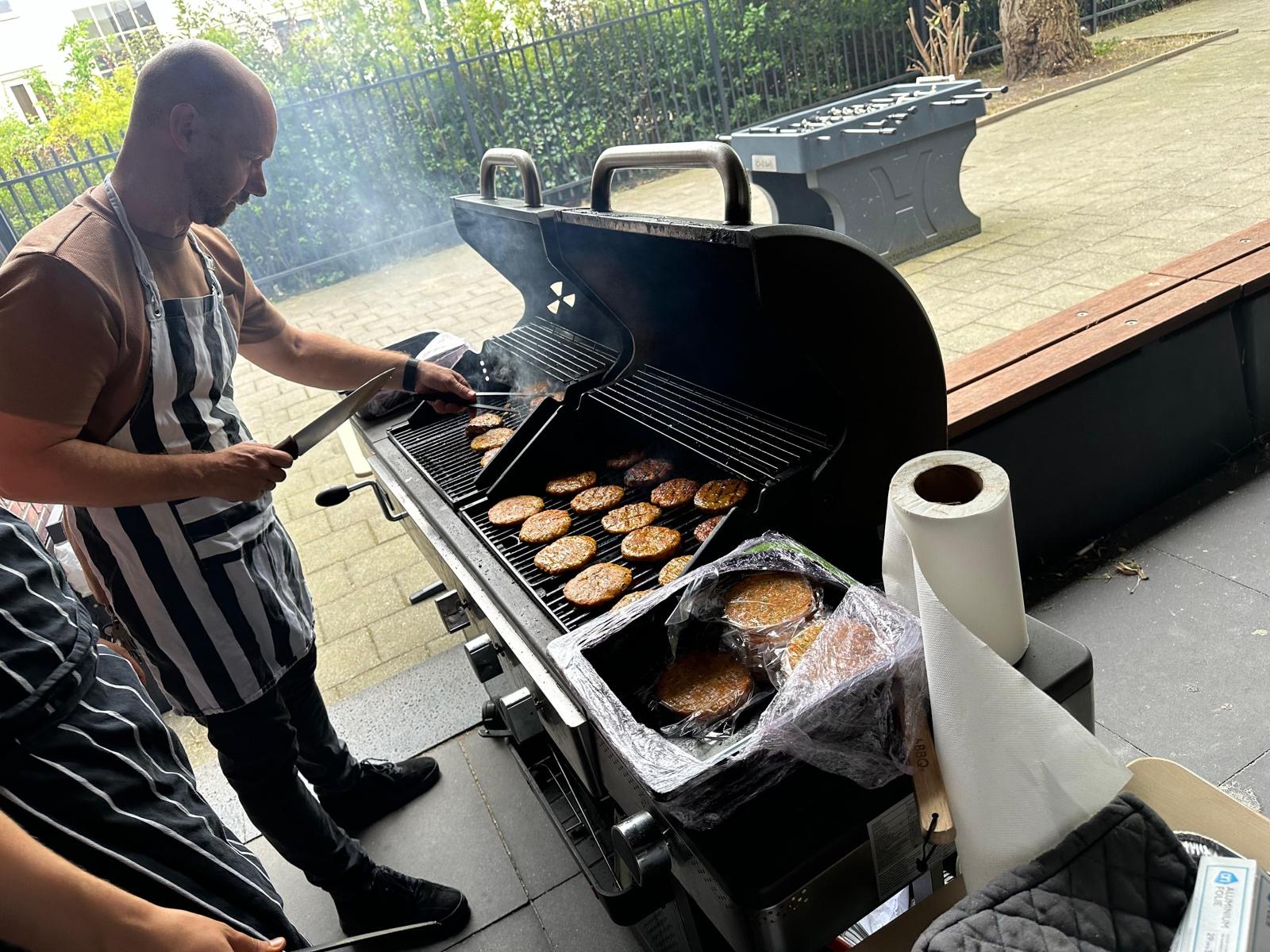 Begeleider bereidt burgers op de barbecue voor de feestelijke afsluiting